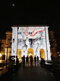 People walking on illuminated street at night