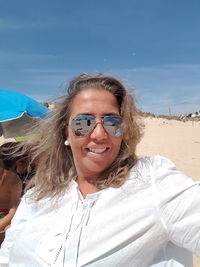 Portrait of smiling young woman on beach against sky