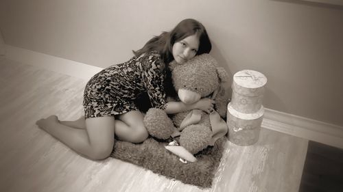 Full length portrait of beautiful woman with teddy bear at home