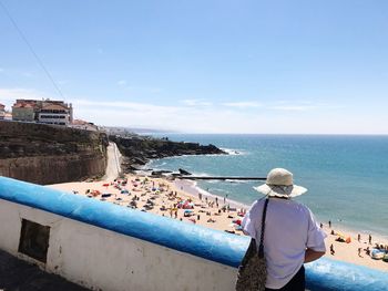 Rear view of people at sea shore against sky