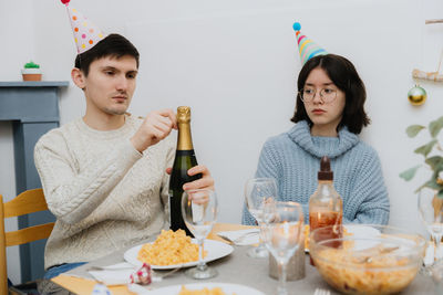 Young people open a bottle of champagne at the table.