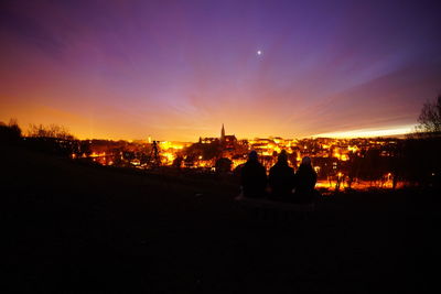 Illuminated city against sky during sunset