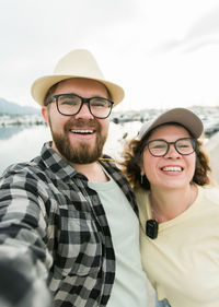 Portrait of smiling friends standing against sky