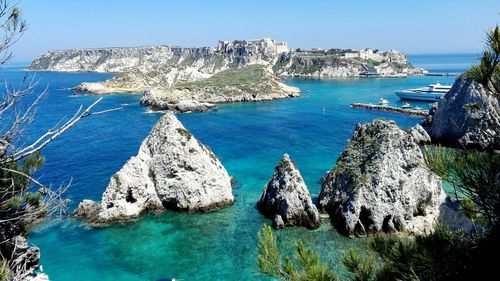 Scenic view of large rocks in blue sea against clear sky