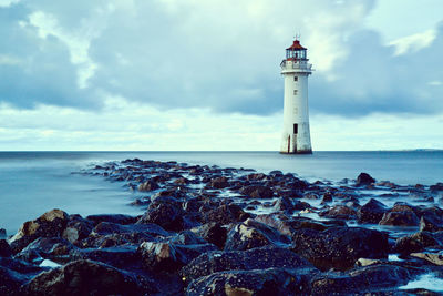 Lighthouse by sea against sky