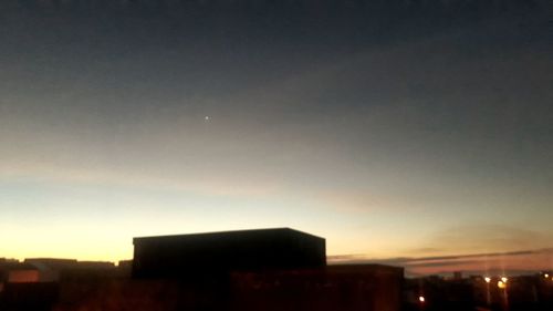 Silhouette buildings against sky at dusk