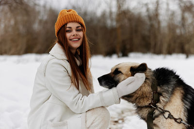 Portrait of young woman with dog on snow
