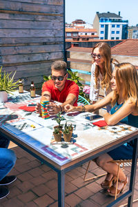 Group of friends playing with jenga game in rooftop on a summer party