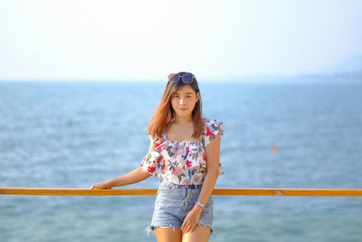 Portrait of smiling young woman standing against sea