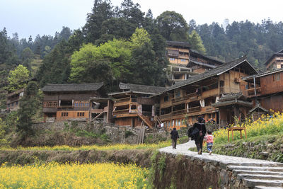People outside house amidst trees and buildings