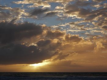 Scenic view of sea against dramatic sky during sunset