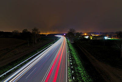 Light trails on road against sky at night