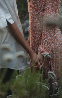 Midsection of woman holding hands while standing at park