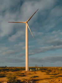 Windmills on field against blue sky