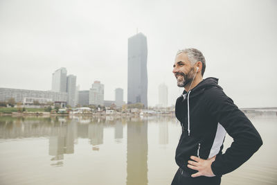 Man standing by sea against sky in city