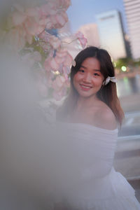 Portrait of young woman standing against white background