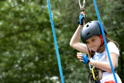 Adventure climbing high wire park - people on course in mountain helmet and safety equipment.