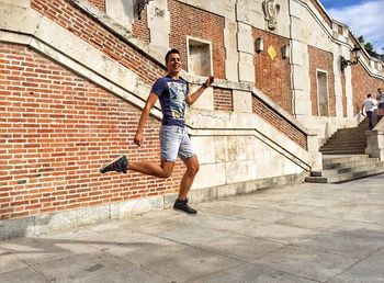 Full length of young woman jumping on wall