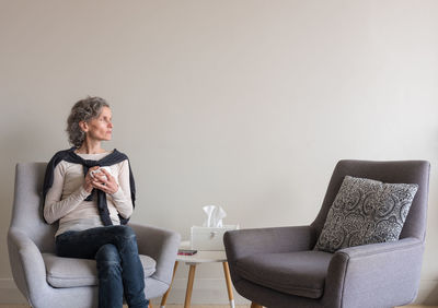 Full length of man sitting on sofa at home