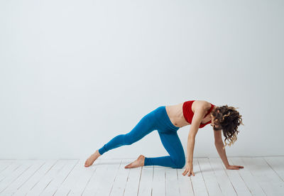 Rear view of woman doing yoga against white background