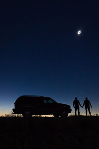 Silhouette people on field against clear sky at night