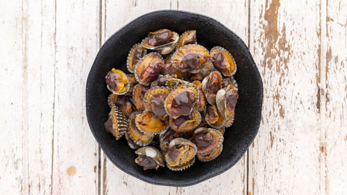 Fresh steamed cockles, boiled cockles in ceramic plate on white wood background, blood cockle