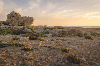 Rock formation by sea against sky during sunset