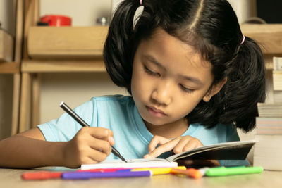 Cute girl drawing on book at home
