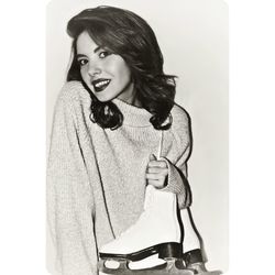 Portrait of happy young woman holding ice skates against gray background