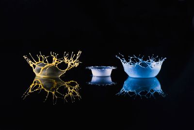 Close-up of illuminated lamp on table against black background