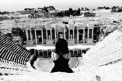 Rear view of woman sitting at historic old ruin