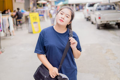 Portrait of young woman standing in city