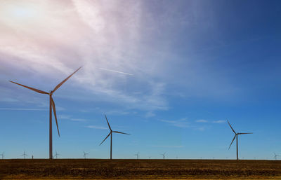 Wind turbines on field against sky