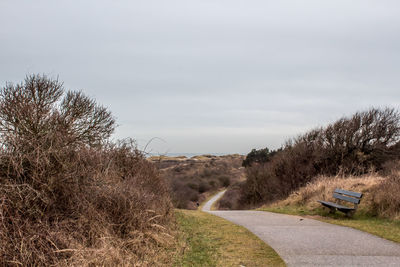 Road amidst trees on field against sky