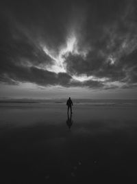 Rear view of man walking at beach against sky