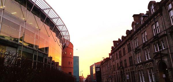 Low angle view of buildings against clear sky at sunset