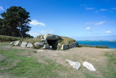 Stone structure on rock by sea against sky