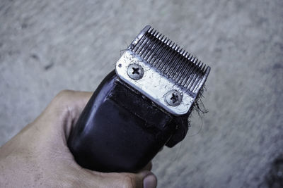 Cropped hand of man holding electric razor with hairs