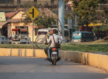 Rear view of man riding bicycle on road