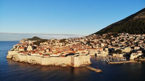 Aerial view of townscape by sea against clear sky