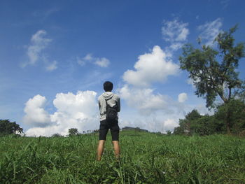 Rear view of man on field against sky