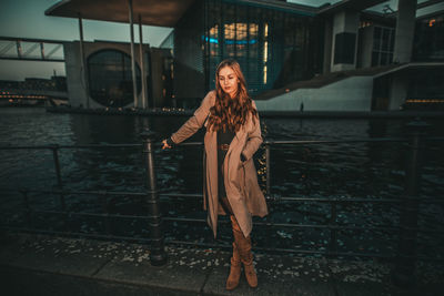 Portrait of young woman standing against railing