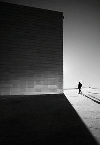 Silhouette man walking by building