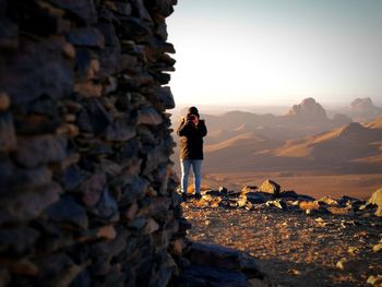 Full length of man photographing with smart phone while standing at desert