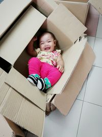 High angle view of baby girl in cardboard box