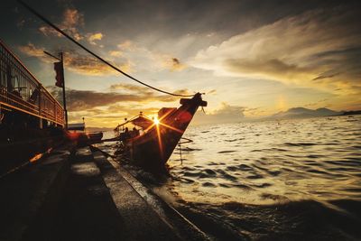 Boat moored on beach against sky during sunset