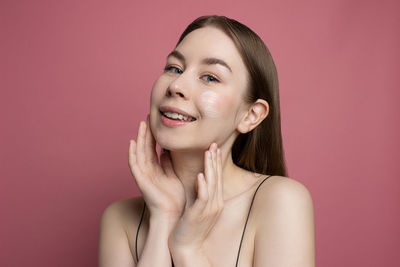 Portrait of young woman against pink background