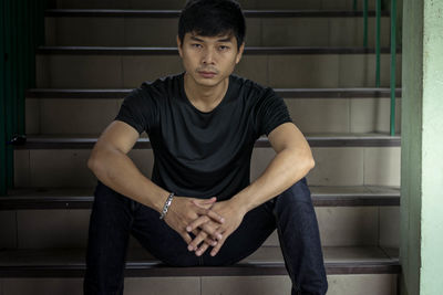 Portrait of young man sitting on seat at home