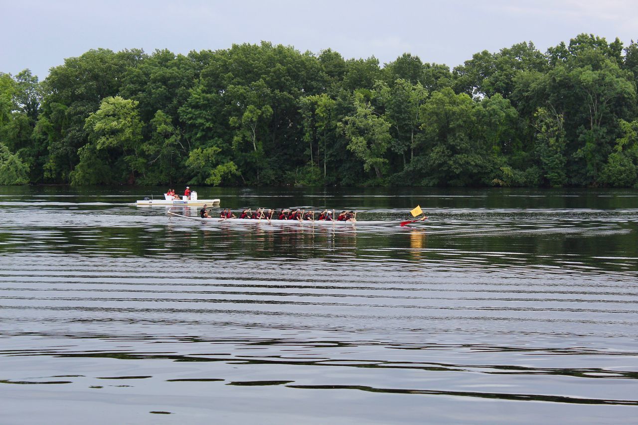 GROUP OF PEOPLE ON BOAT AGAINST LAKE