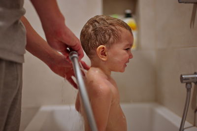 Cute little toddler having shower in bathtub
